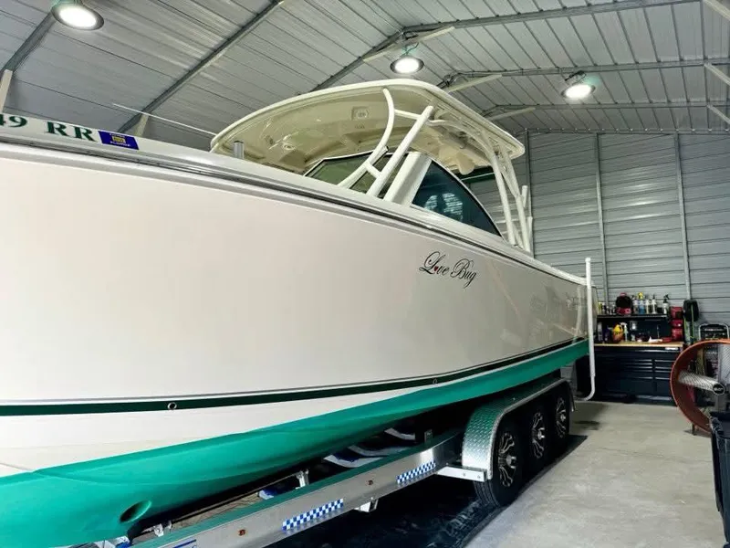 Slide: The Image of 2018 Sailfish 325 DC boat in a garage, on a trailer, with green accents. - 14