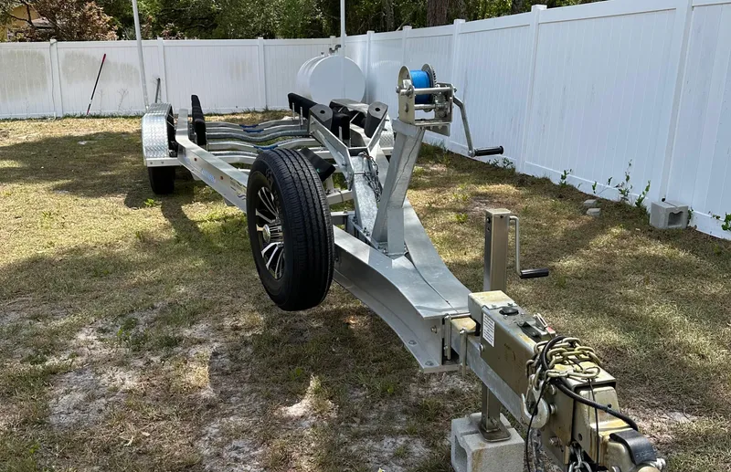 Slide: The Image of Boat trailer for 2018 Sailfish 325 DC, parked on grass near white fence. - 18