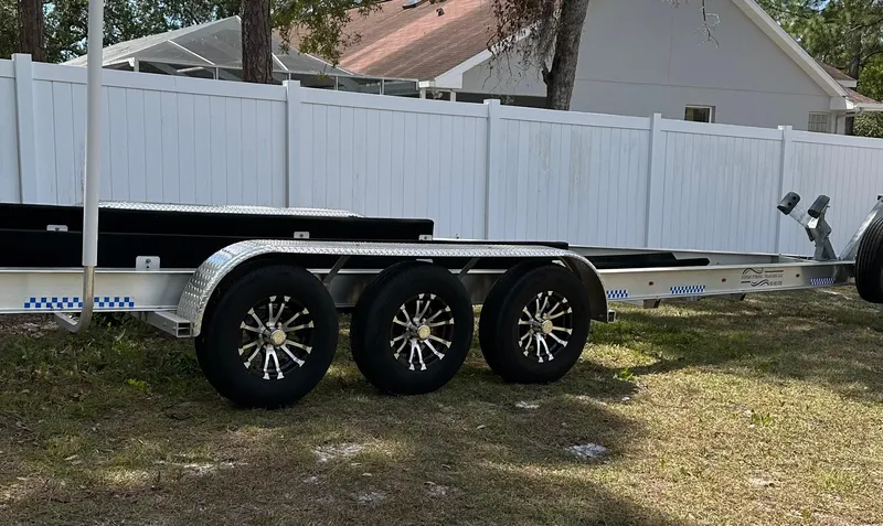 Slide: The Image of Triple-axle boat trailer parked on grass, near a white fence, suitable for Sailfish 325 DC. - 22