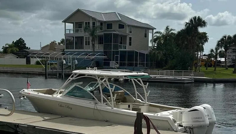 Slide: The Image of 2018 Sailfish 325 DC boat docked near a waterfront house with palm trees. - 25