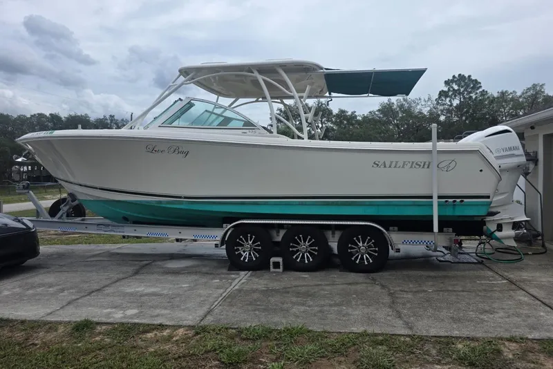 Slide: The Image of 2018 Sailfish 325 DC boat on trailer, parked outdoors, featuring dual Yamaha engines. - 0