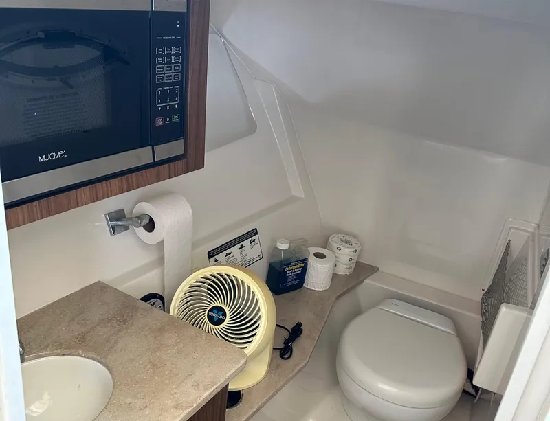 Slide: The Image of 2018 Sailfish 325 DC boat bathroom with sink, toilet, fan, and microwave. - 7