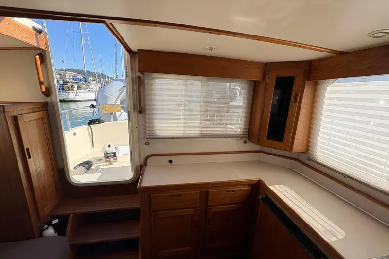Slide: The Image of Interior of a 2004 Nordic Tug 32 with wooden cabinetry and marina view. - 19
