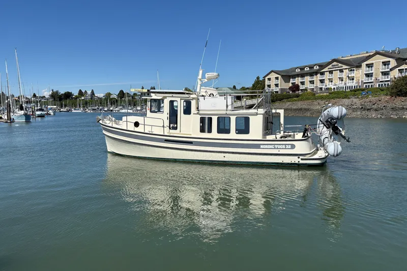 Slide: The Image of 2004 Nordic Tug 32 boat on calm water near marina and buildings. - 2