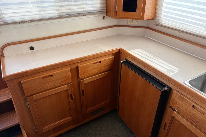 Slide: The Image of 2004 Nordic Tug 32 interior kitchen with wooden cabinets and compact refrigerator. - 21