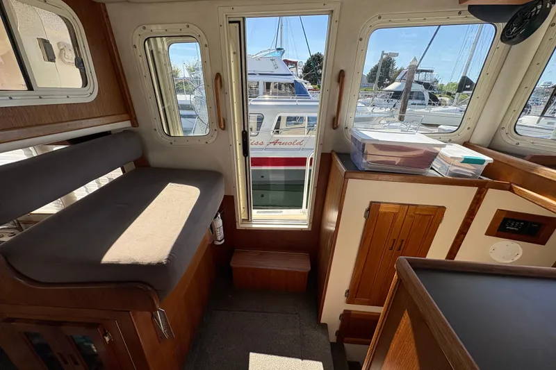Slide: The Image of Interior of a 2004 Nordic Tug 32, showcasing seating and storage with marina view. - 28