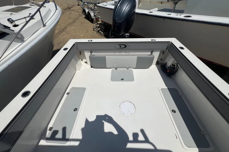 Slide: The Image of 2026 Defiance Admiral 220 EX boat deck with storage compartments and motor, docked outdoors. - 10