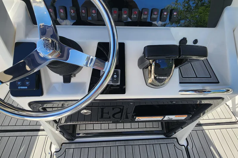 Slide: The Image of 2022 Yamaha 255 FSH Sport E boat dashboard with steering wheel and controls. - 12