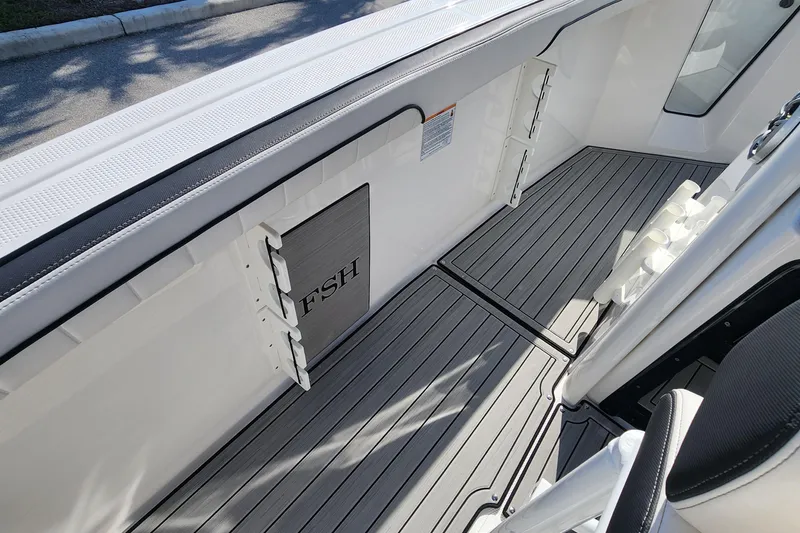 Slide: The Image of 2022 Yamaha 255 FSH Sport E boat interior with sleek gray flooring and storage compartments. - 13
