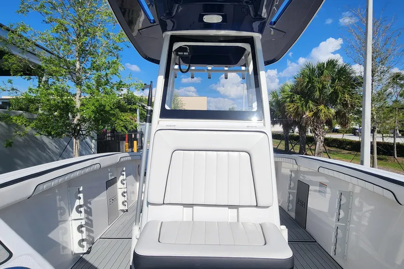 Slide: The Image of 2022 Yamaha 255 FSH Sport E boat interior with seating and console, under a clear blue sky. - 26