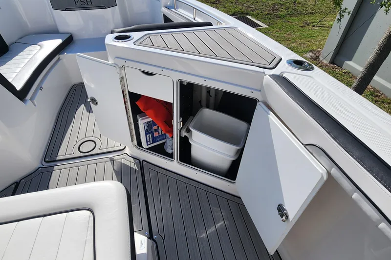Slide: The Image of 2022 Yamaha 255 FSH Sport E boat interior storage compartments open, revealing safety gear. - 30