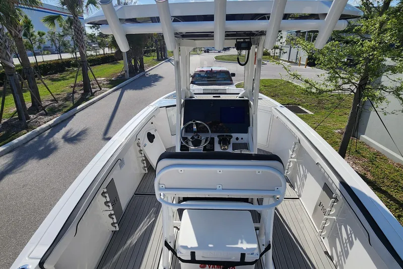 Slide: The Image of 2022 Yamaha 255 FSH Sport E boat interior with helm and seating, parked outdoors. - 36