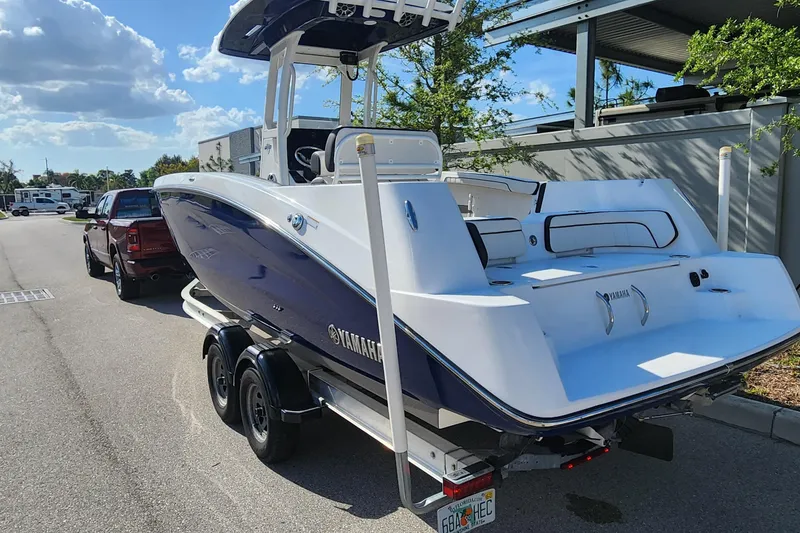 Slide: The Image of 2022 Yamaha 255 FSH Sport E boat on trailer, parked outdoors under a sunny sky. - 4