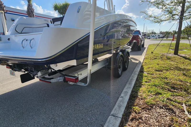Slide: The Image of 2022 Yamaha 255 FSH Sport E boat on trailer, parked outdoors on a sunny day. - 40