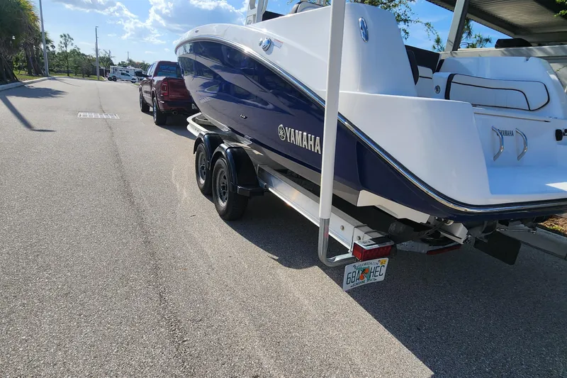 Slide: The Image of 2022 Yamaha 255 FSH Sport E boat on trailer, parked on sunny street. - 42