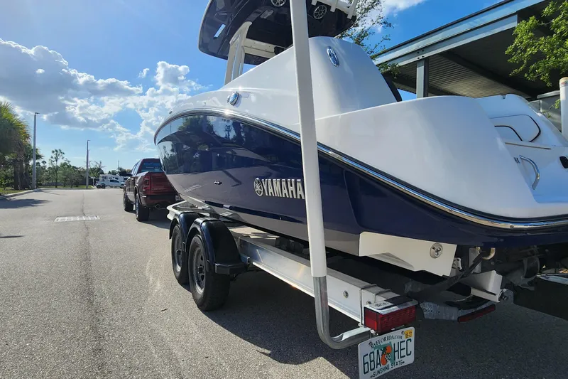 Slide: The Image of 2022 Yamaha 255 FSH Sport E boat on trailer, parked on sunny street. - 43