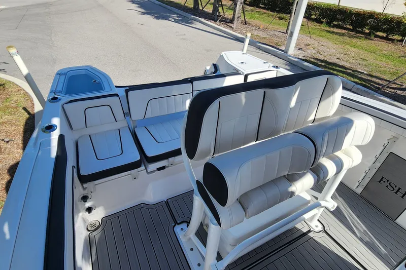 Slide: The Image of 2022 Yamaha 255 FSH Sport E boat interior with white cushioned seating and sleek design. - 6