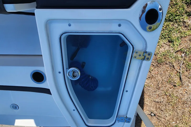 Slide: The Image of 2022 Yamaha 255 FSH Sport E boat storage compartment with blue interior and latch. - 9