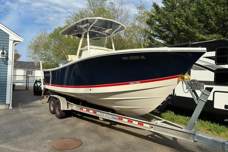 Slide: The Image of 2019 Regulator 23 boat on trailer, parked outdoors near a house and RV. - 17