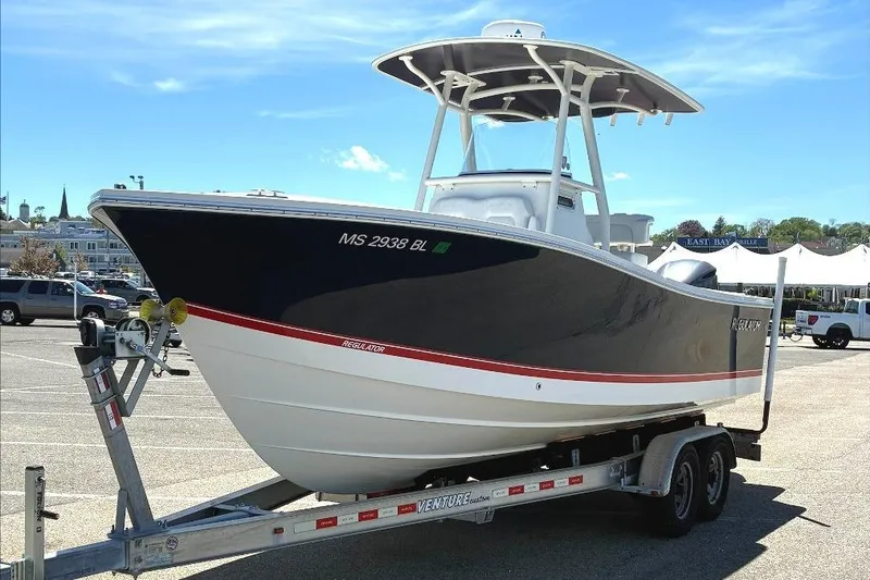Slide: The Image of 2019 Regulator 23 boat on trailer in parking lot under clear blue sky. - 3