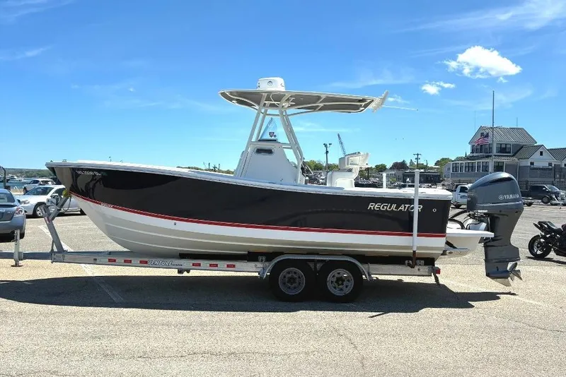 Slide: The Image of 2019 Regulator 23 boat on trailer, parked outdoors under clear blue sky. - 4