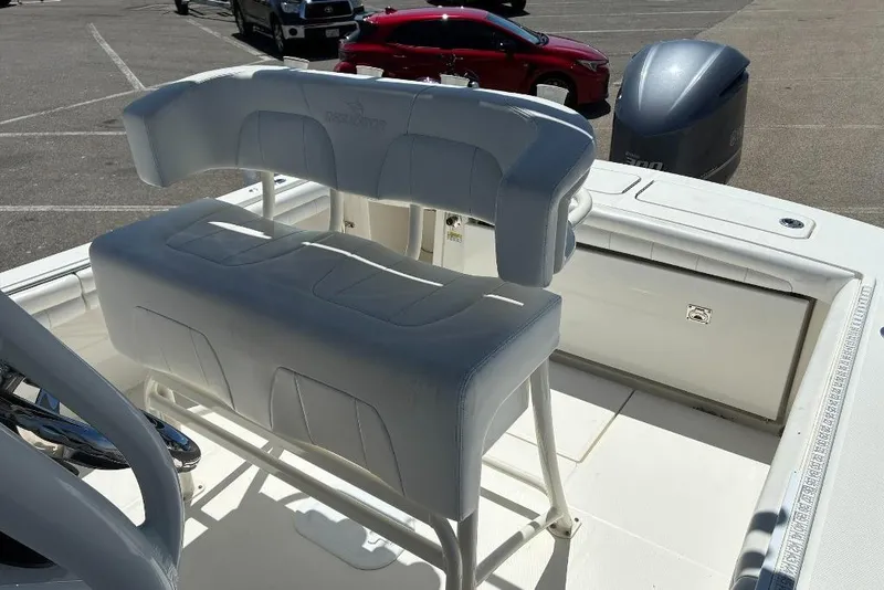 Slide: The Image of 2019 Regulator 23 boat interior with cushioned seating and engine in parking lot. - 9