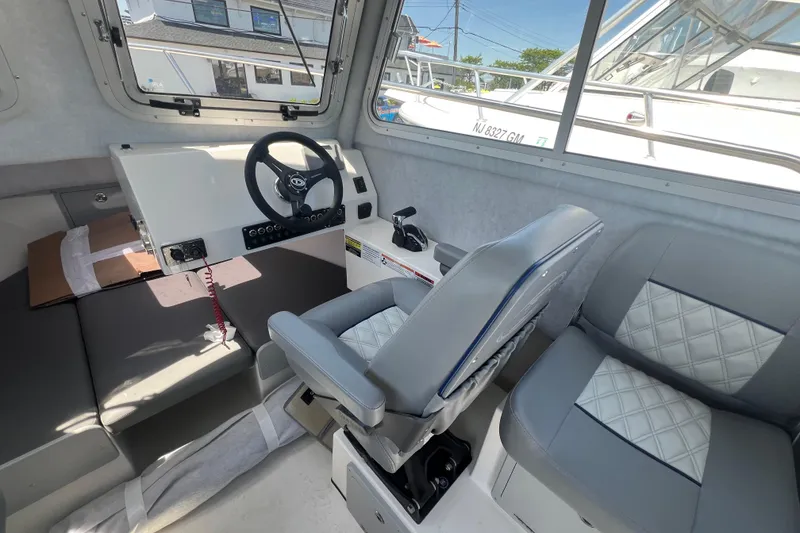 Slide: The Image of Interior of 2026 Defiance Admiral 220 EX boat, featuring steering wheel and cushioned seating. - 13