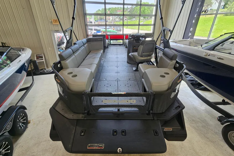 Slide: The Image of 2023 Sea-Doo Switch Cruise 21 pontoon boat interior with seating and helm in showroom. - 4