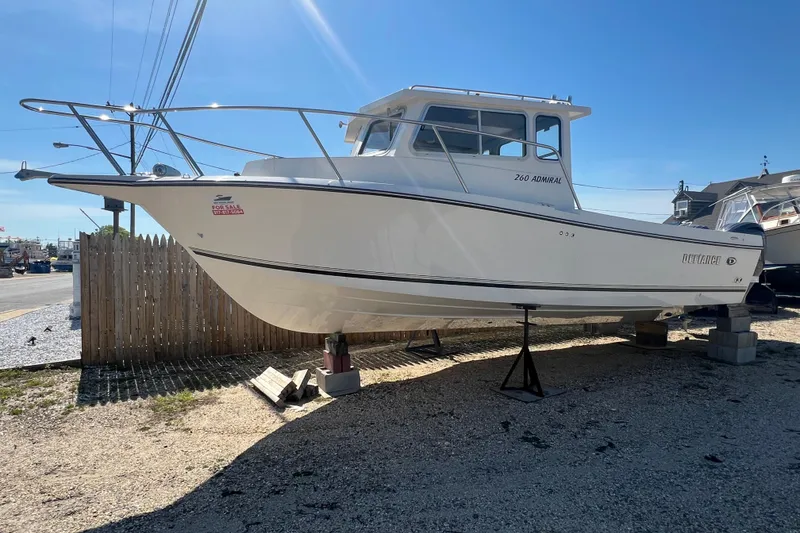 The Image of 2025 Defiance Admiral 260 EX boat on display, elevated on blocks, with "For Sale" sign. - 0