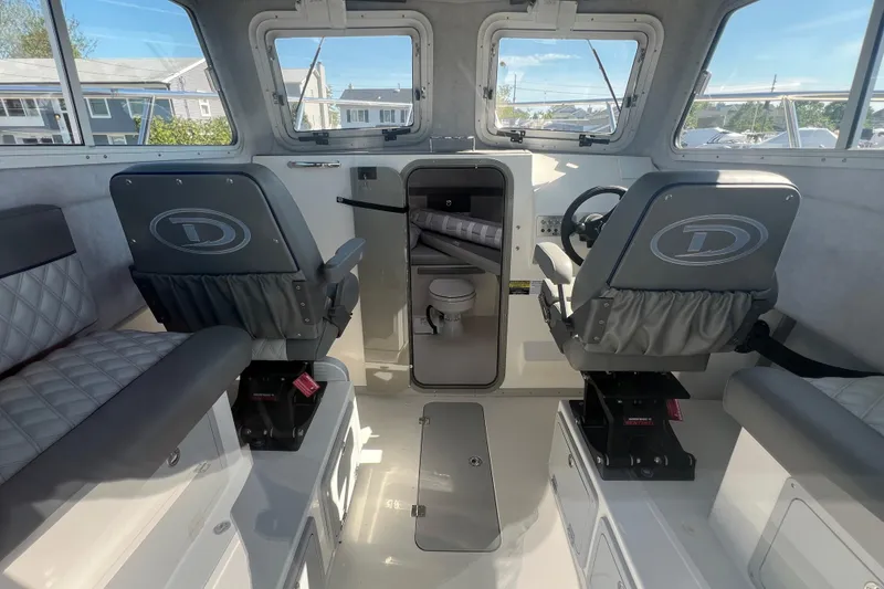 Slide: The Image of Interior of 2025 Defiance Admiral 260 EX boat with seating and steering area. - 2