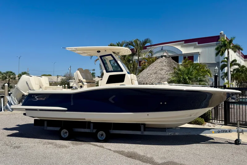 Slide: The Image of 2026 Scout 260 LXF boat on trailer, parked outdoors under clear blue sky. - 2