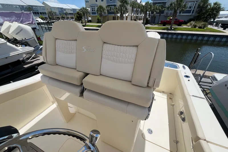 Slide: The Image of 2026 Scout 260 LXF boat interior with beige seating and steering wheel, dockside view. - 20
