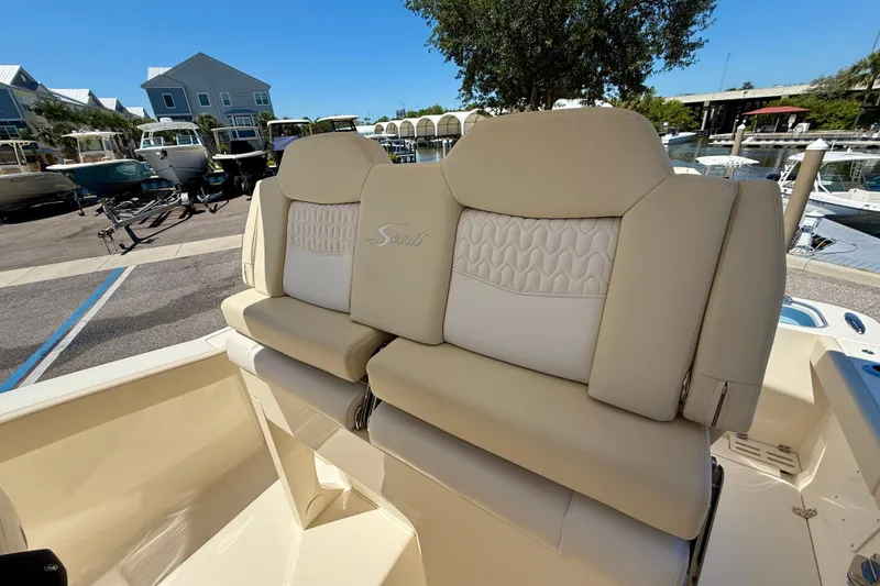 Slide: The Image of 2026 Scout 260 LXF boat seats with beige upholstery at a marina. - 21