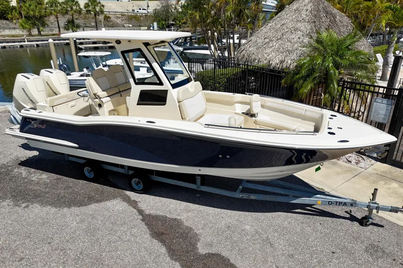 Slide: The Image of 2026 Scout 260 LXF boat on trailer, parked near marina with tropical surroundings. - 3