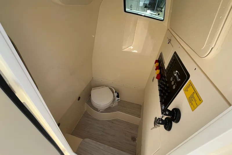 Slide: The Image of Interior of 2026 Scout 260 LXF boat, featuring a compact marine toilet and control panel. - 31