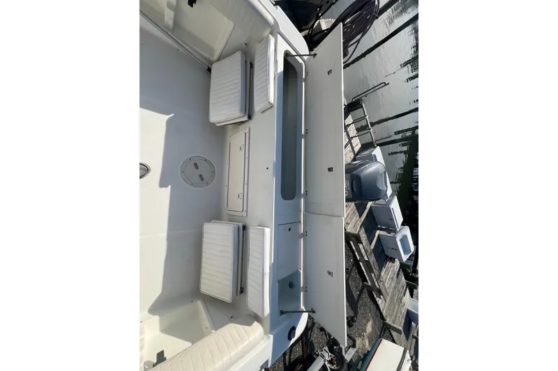 Slide: The Image of 2000 Hydra-Sports 230 Seahorse CC boat interior with seating and storage, docked by the water. - 22
