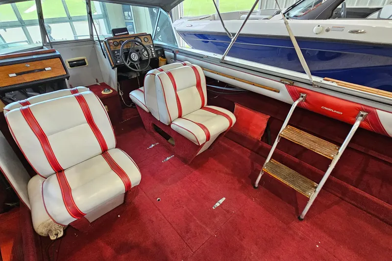 Slide: The Image of 1988 Crestliner 2281 boat interior with red and white seats, wooden accents, and steering wheel. - 10