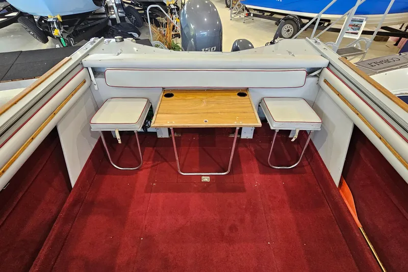 Slide: The Image of 1988 Crestliner 2281 boat interior with red carpet, foldable table, and seating. - 15