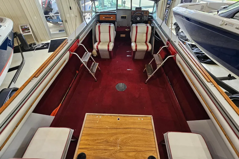 Slide: The Image of 1988 Crestliner 2281 boat interior with red carpet and striped seats in a showroom. - 16