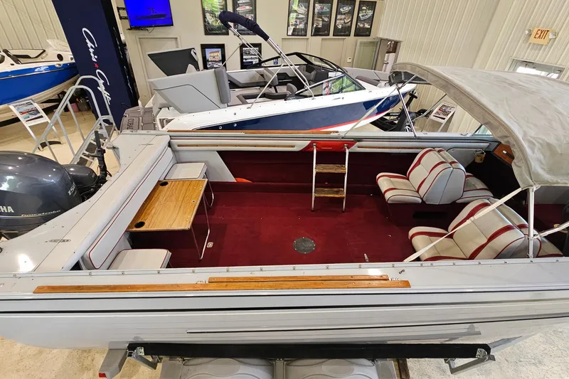 Slide: The Image of 1988 Crestliner 2281 boat interior with red carpet, seating, and wooden table in showroom. - 17