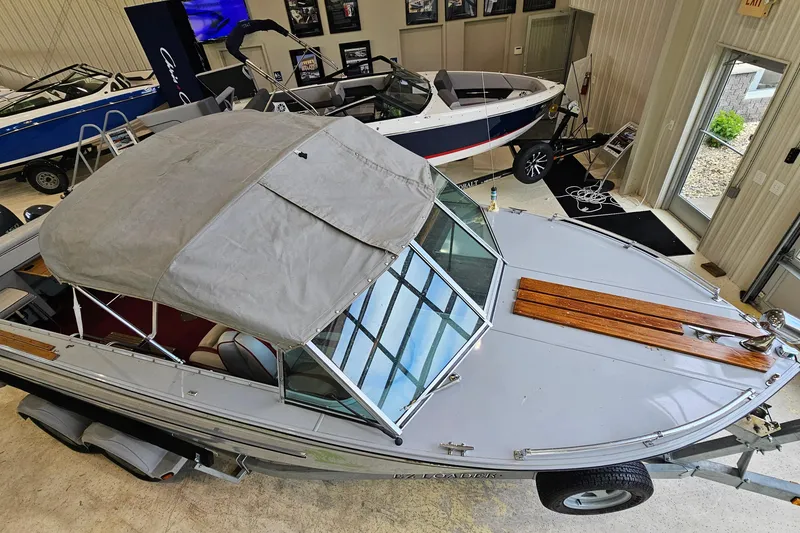 Slide: The Image of 1988 Crestliner 2281 boat with canopy, displayed indoors alongside other boats. - 18