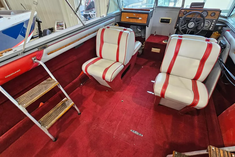 Slide: The Image of 1988 Crestliner 2281 boat interior with red carpet, white seats, and wooden accents. - 9