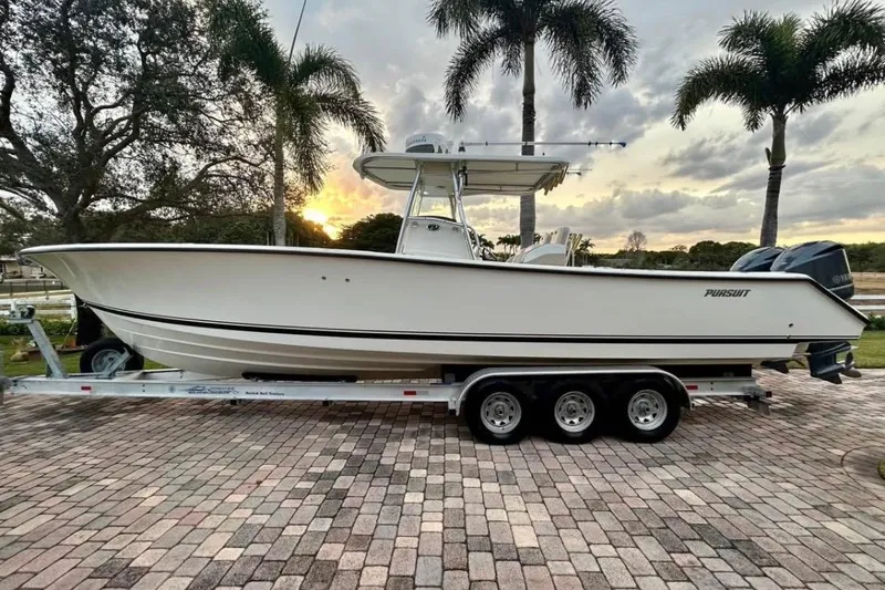 The Image of 2008 Pursuit C 340 Center Console boat on trailer, parked with palm trees in background. - 0