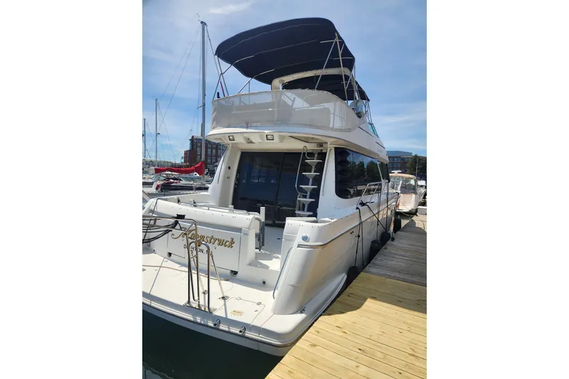 Slide: The Image of 1998 Carver 530 Voyager Pilothouse yacht docked at marina, rear view with blue canopy. - 4
