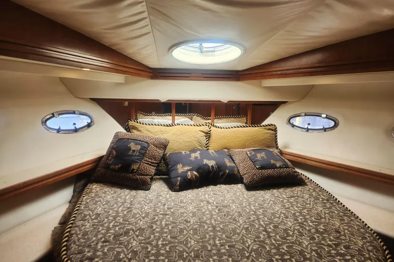 Slide: The Image of Luxurious 1998 Carver 530 Voyager Pilothouse bedroom with elegant bedding and porthole windows. - 7