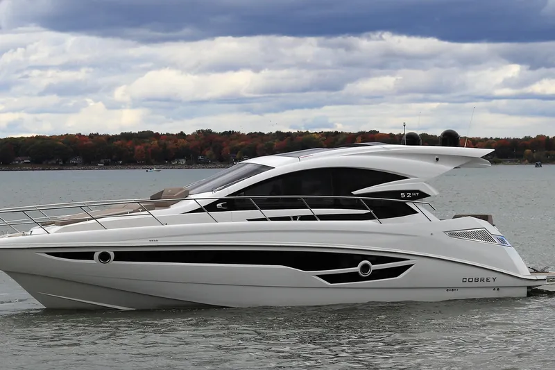 The Image of Luxury 2026 Cobrey 52 HT yacht on a serene lake with autumn foliage backdrop. - 0