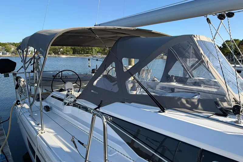 Slide: The Image of 2022 Bavaria C38 sailboat with canopy docked in a serene marina setting. - 9