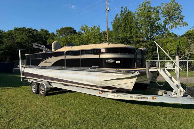 The Image of 2017 Manitou 25 Legacy pontoon boat on trailer, parked on grass with trees in background. - 11