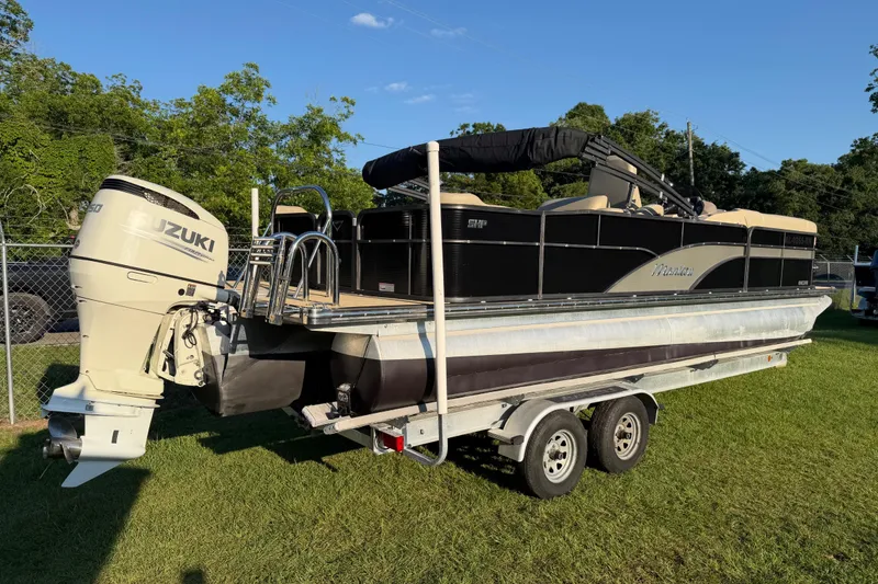 Slide: The Image of 2017 Manitou 25 Legacy pontoon boat with Suzuki engine on a trailer, parked on grass. - 13