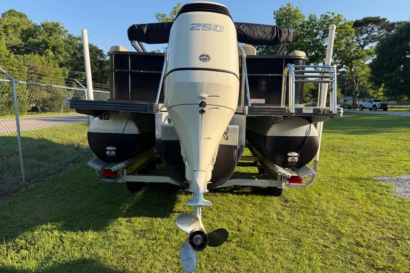 Slide: The Image of 2017 Manitou 25 Legacy pontoon boat with 250 horsepower engine on a grassy area. - 14
